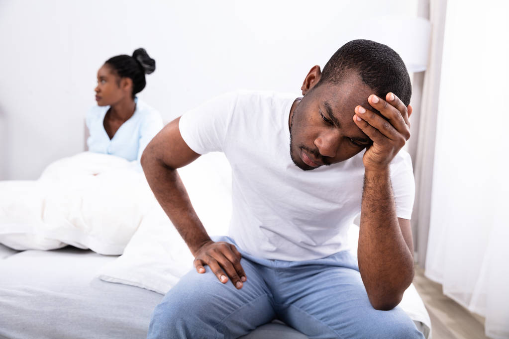 Jong Afrikaans man zit op bed in de voorkant van zijn vrouw - Foto, afbeelding