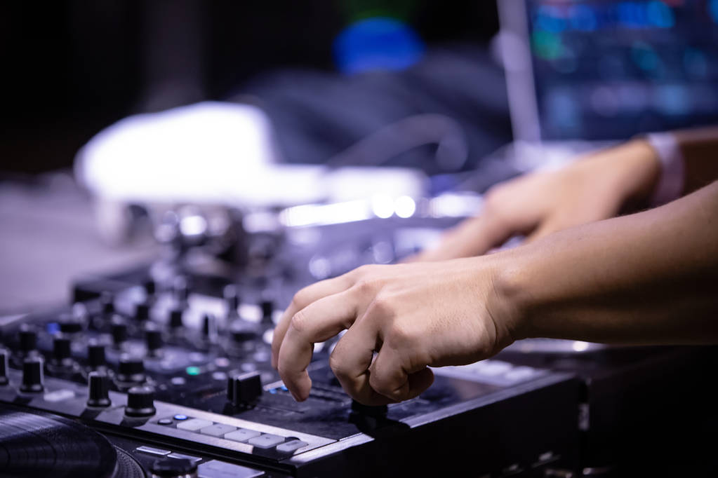 Hip-Hop Party-DJ zerkratzt Schallplatte mit Musik auf der Bühne im Nachtclub.Hände von Discjockey mischen Musiktitel mit Soundmixer und Retro-Plattenspielern - Foto, Bild