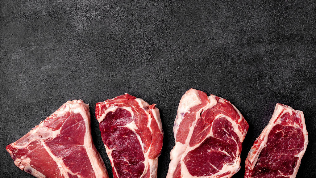 Fleisch roh Steak liegt auf einem schwarzen Hintergrund. Seitenansicht, Kopierraum, Draufsicht - Foto, Bild