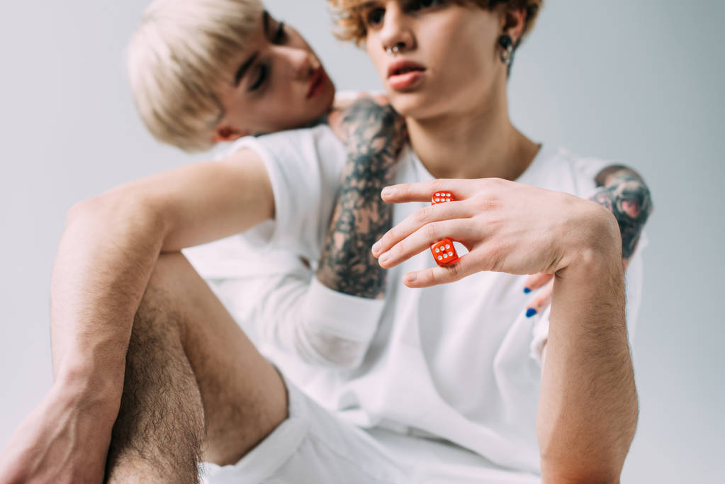 επιλεκτική εστίαση κόκκινα ζάρια στο χέρι του ανθρώπου κοντά τατουάζ κορίτσι που απομονώνονται σε γκρι - Φωτογραφία, εικόνα