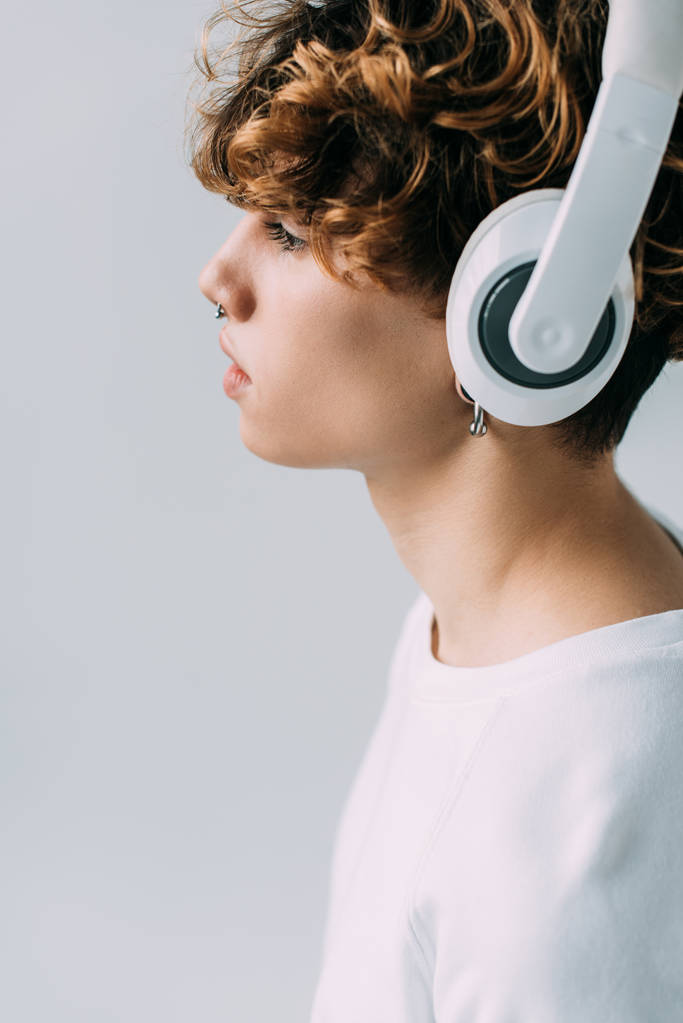 side view of handsome man listening music in headphones isolated on grey  - Photo, Image