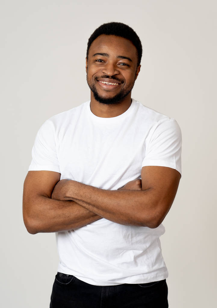 Half length portrait of attractive shy young african american man with happy face flirting with beautiful smile posing and looking at camera. People, Positive emotions and human facial expressions. - Photo, Image