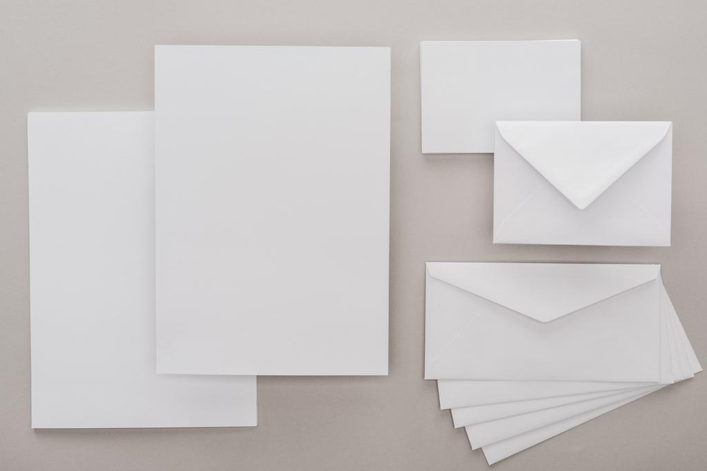 top view of white empty papers and envelopes on grey background - Photo, Image