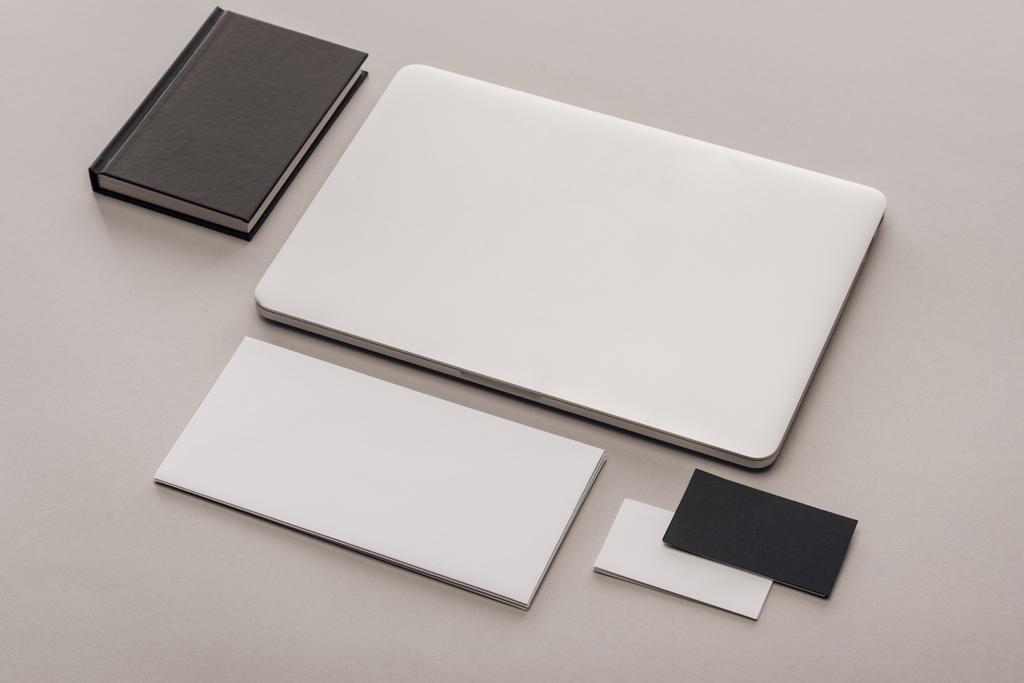 plat posé avec des cartes vides noir et blanc et ordinateur portable sur fond gris
 - Photo, image