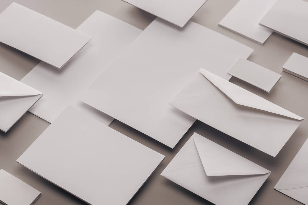 close-up de papéis brancos vazios e envelopes sobre fundo cinza
 - Foto, Imagem