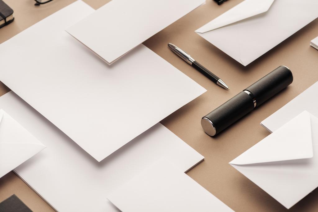 Stylo, étui, enveloppes et feuilles de papier sur fond beige
 - Photo, image