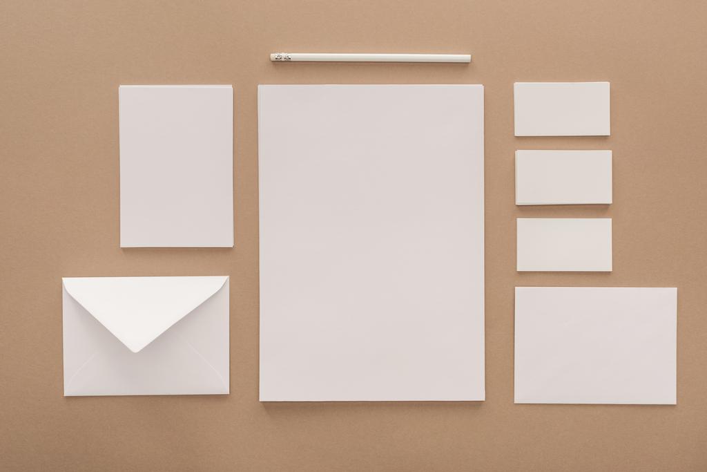 Envelope, pencil, cards and sheets of paper on beige background - Photo, Image