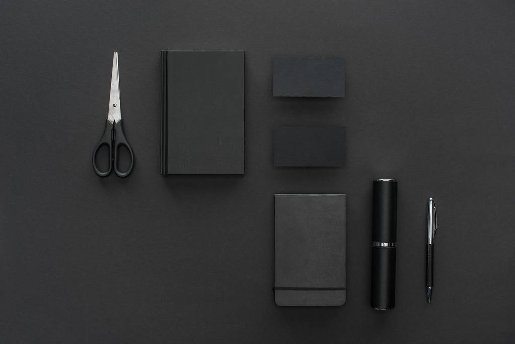 Widok z góry pióro, notebooki, karty i nożyczki na czarnym tle - Zdjęcie, obraz