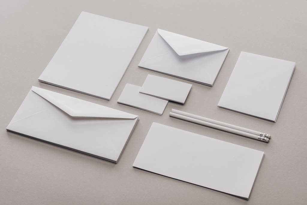 Pose plate avec enveloppes, cartes, feuilles de papier et crayons sur fond gris
 - Photo, image