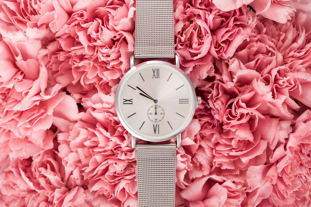 top view of luxury wristwatch lying on blooming flowers - Photo, Image