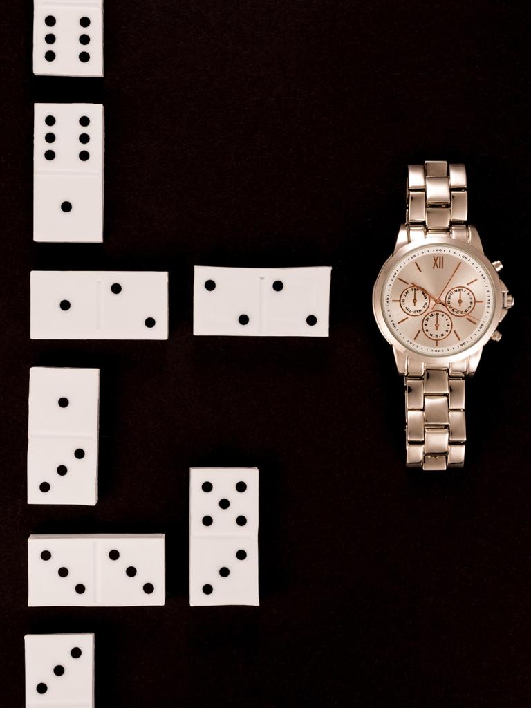 top view of luxury wristwatch lying near dominoes isolated on black - Photo, Image