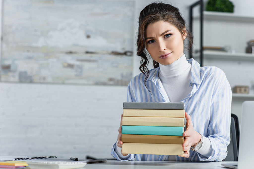 attraktive Frau mit Büchern in der Hand im modernen Büro  - Foto, Bild