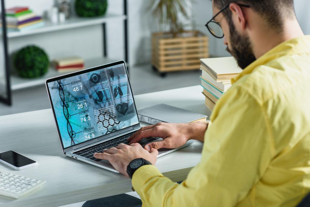 бородатый человек смотрит на ноутбук с медицинским сайтом на экране в современном офисе
 - Фото, изображение
