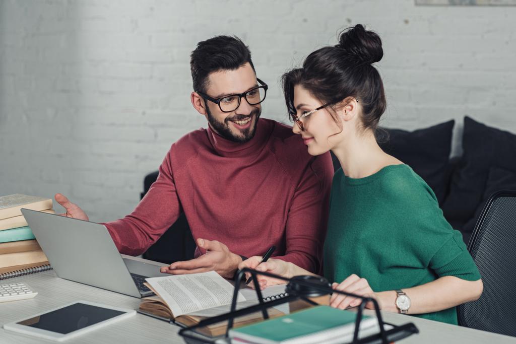 fröhlicher Mann blickt Frau mit Brille in modernem Büro an - Foto, Bild