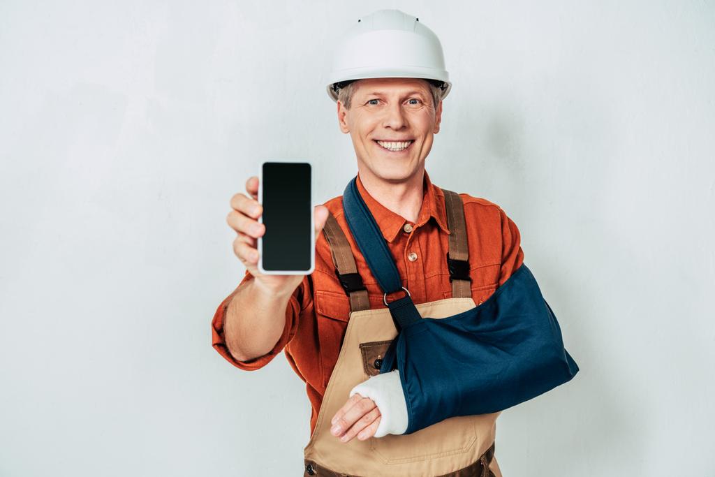 réparateur avec bandage de bras montrant smartphone à fond blanc
 - Photo, image