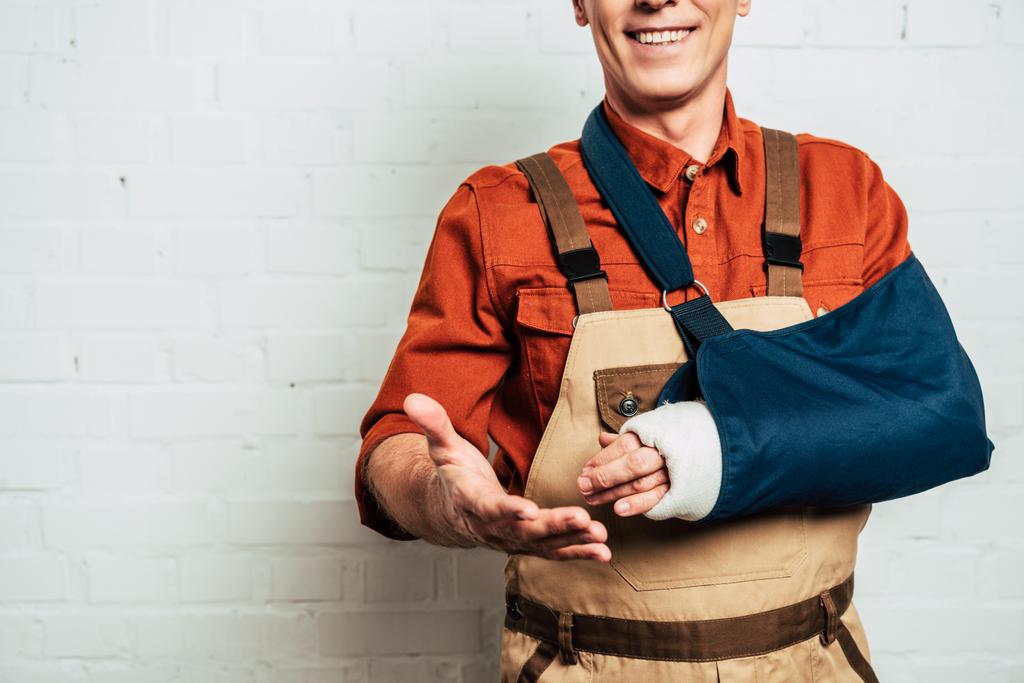 cropped view of repairman with arm bandage standing on white textured background - Photo, Image