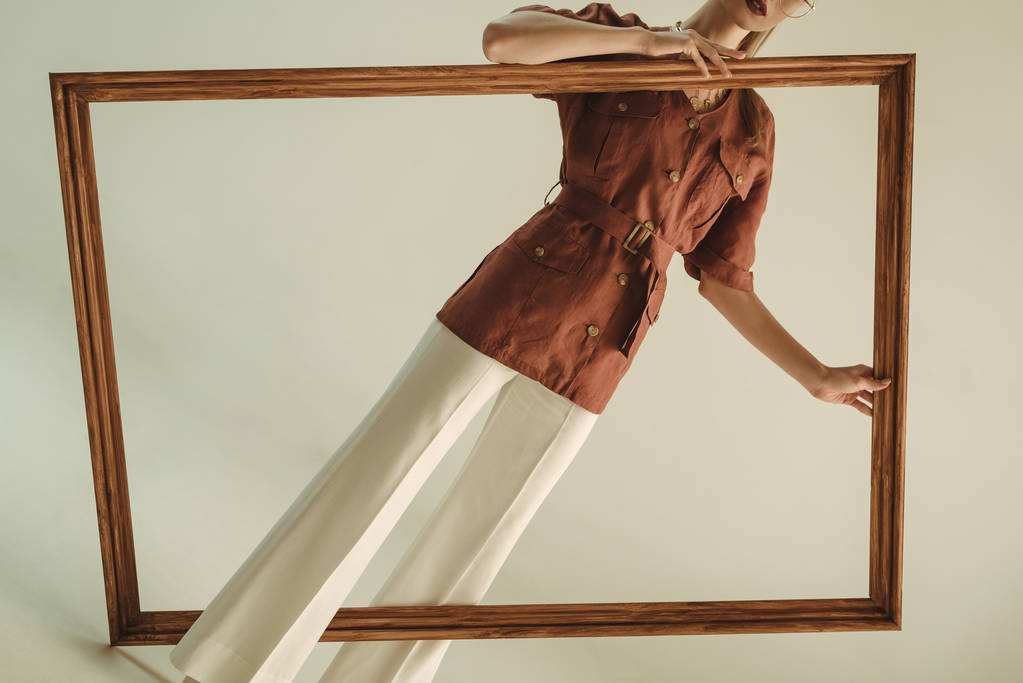 vista recortada de la mujer de moda en estilo vintage posando con marco de madera grande
 - Foto, Imagen