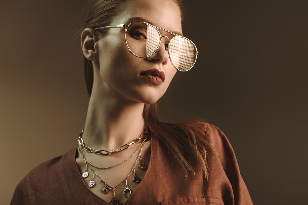 красивая стильная женщина позирует в модных очках изолированы на коричневый
 - Фото, изображение
