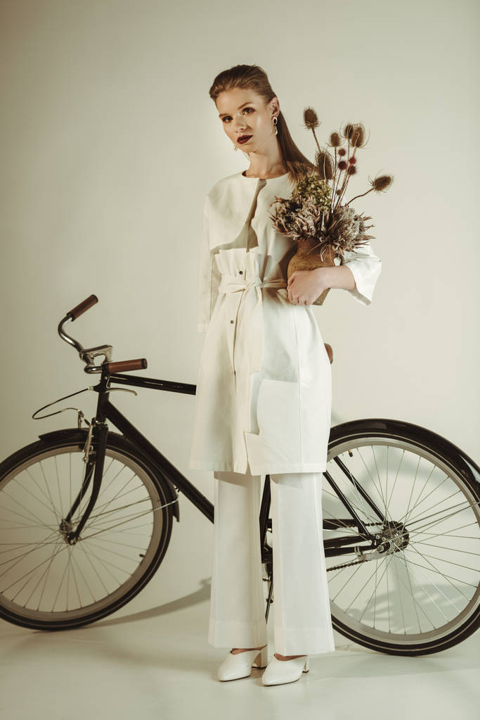 menina na moda posando com buquê de flores secas perto bege
 - Foto, Imagem