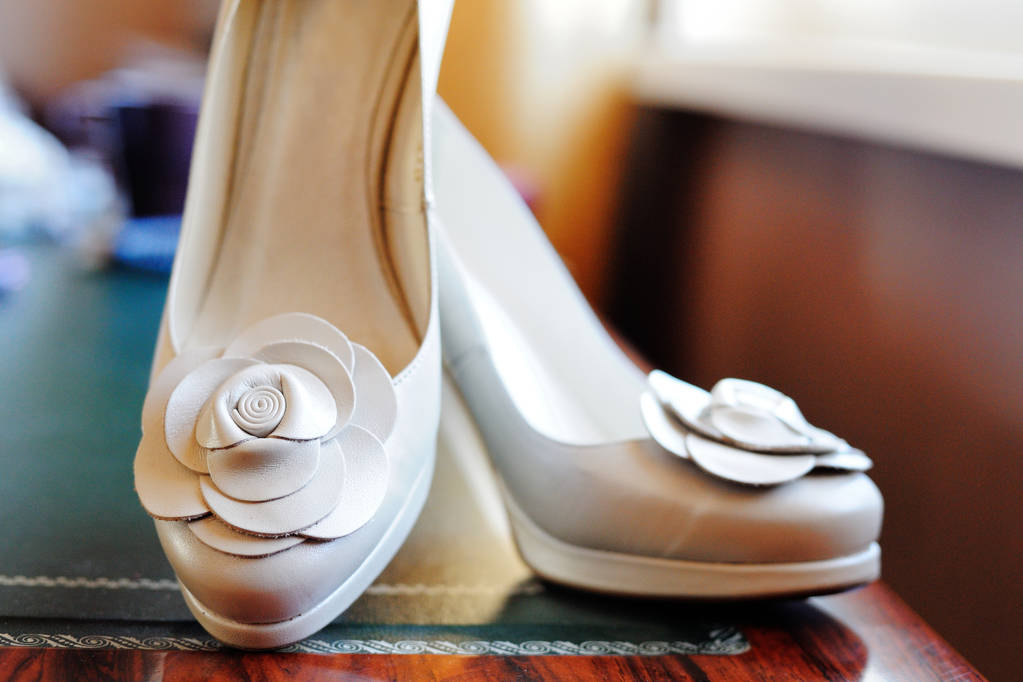 Пара бежевых туфель на каблуках с цветочным декором
. - Фото, изображение