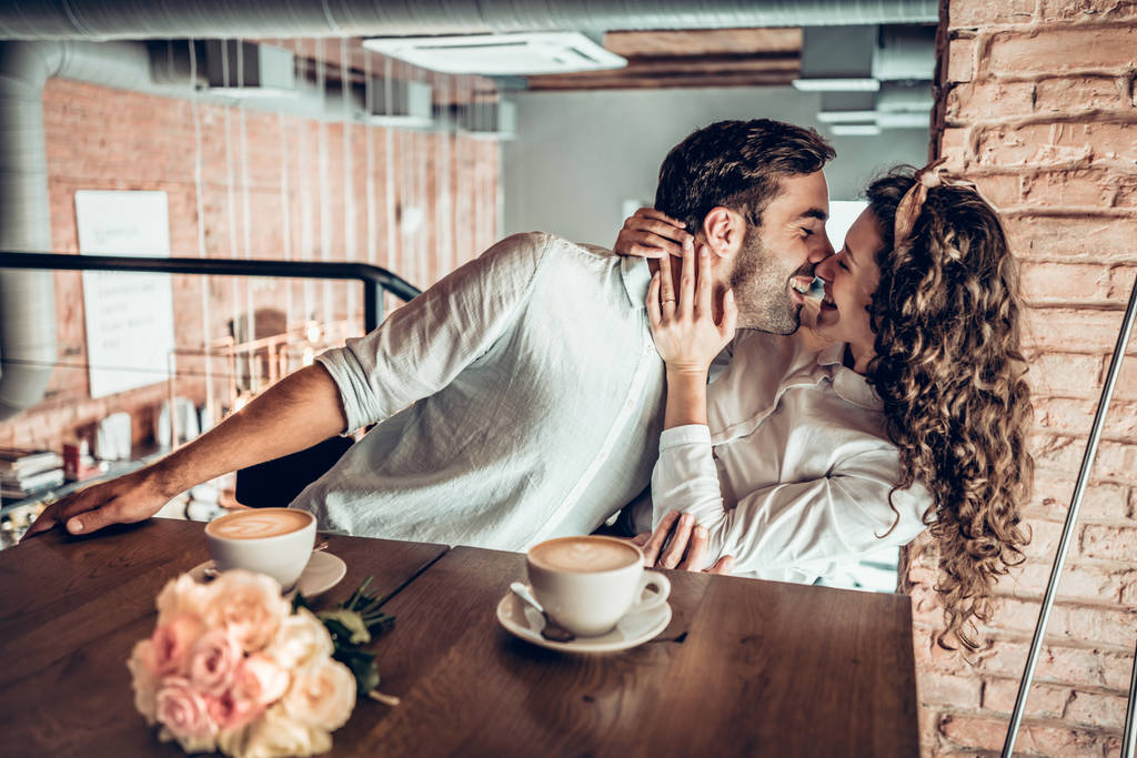 Έννοια της αγάπης. Όμορφο ζευγάρι ρομαντικό φιλιά παιχνιδιάρικα ενώ κάθεται στο καφενείο. - Φωτογραφία, εικόνα