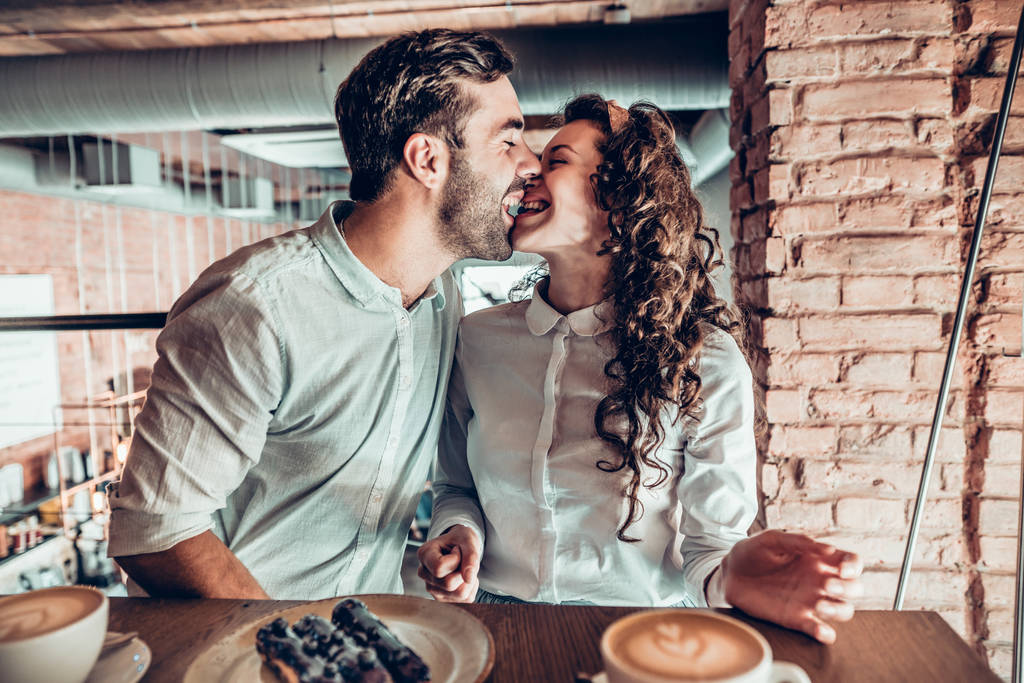 Alegre humor. Una pareja enamorada se está divirtiendo mientras se sienta en un café
. - Foto, Imagen