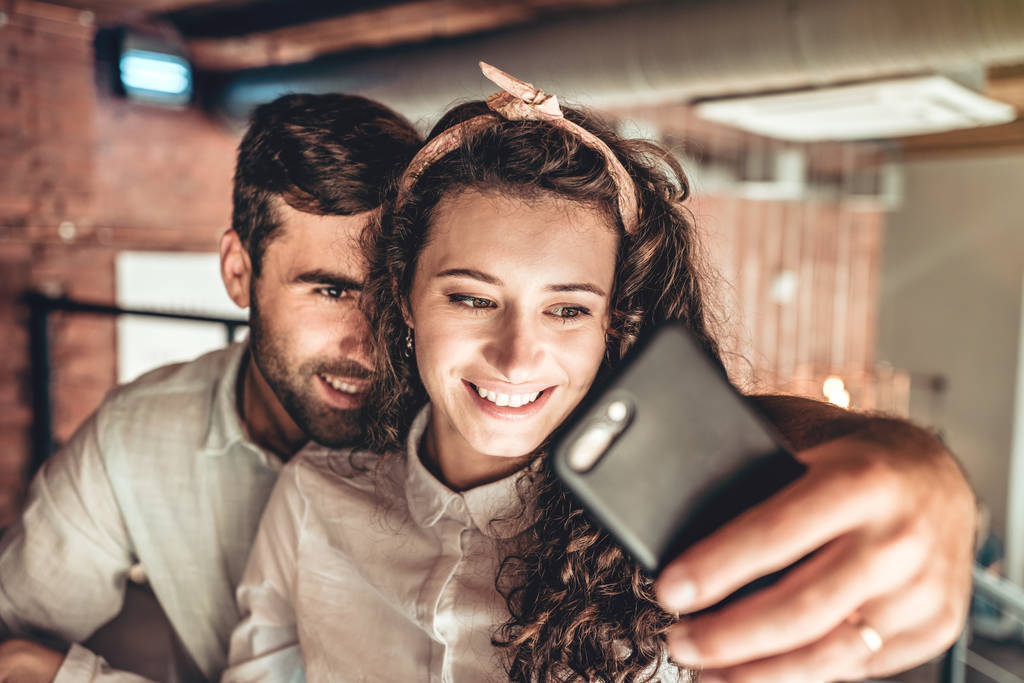 Beau couple faisant du selfie sur un nouveau smartphone. Couple amoureux passe du temps dans un café
. - Photo, image