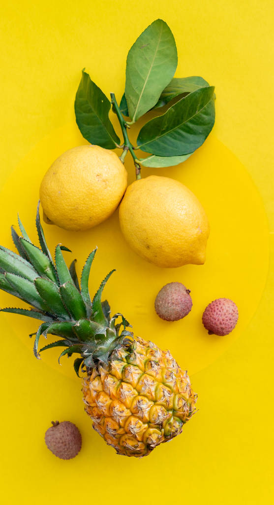 Fresh ripe exotic fruits with leaves on the yellow background - Photo, Image