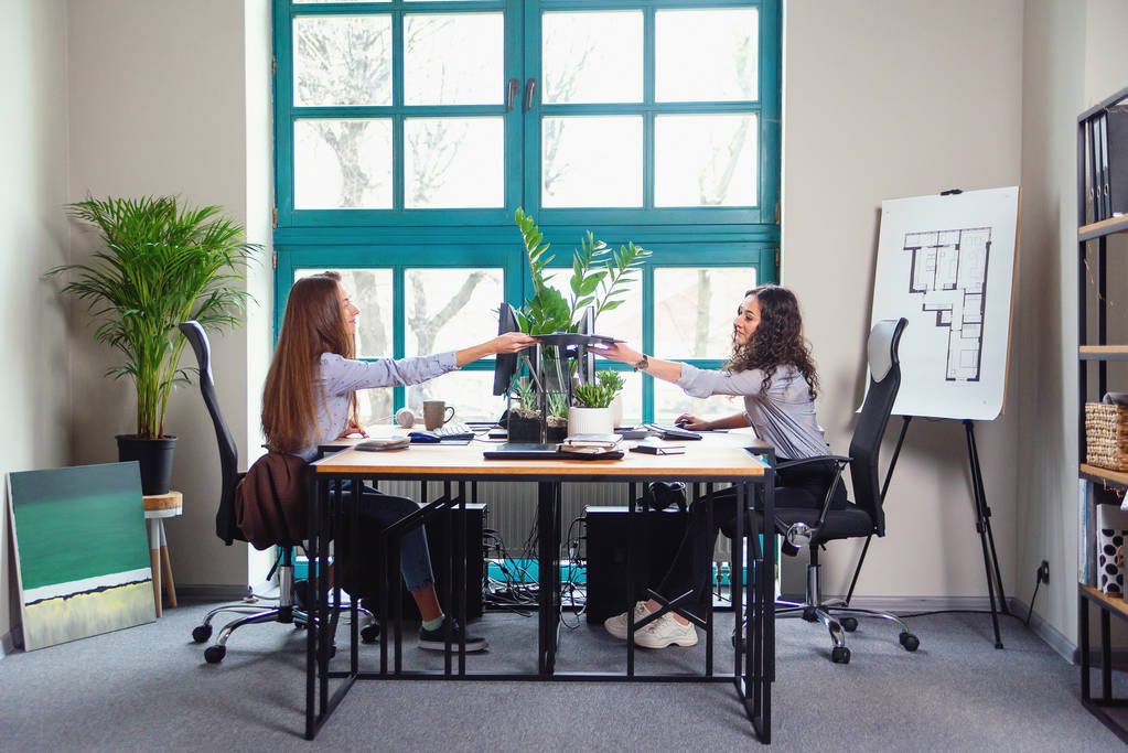 近代的なオフィスで働く 2 人の白人女性デザイナー。一人の女の子が別のカラー パレットを与える. - 写真・画像