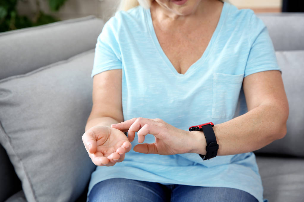 Mujer madura comprobando el pulso con los dedos en casa, primer plano
 - Foto, imagen