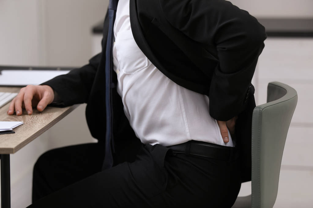 Businessman suffering from back pain at workplace, closeup - Photo, Image