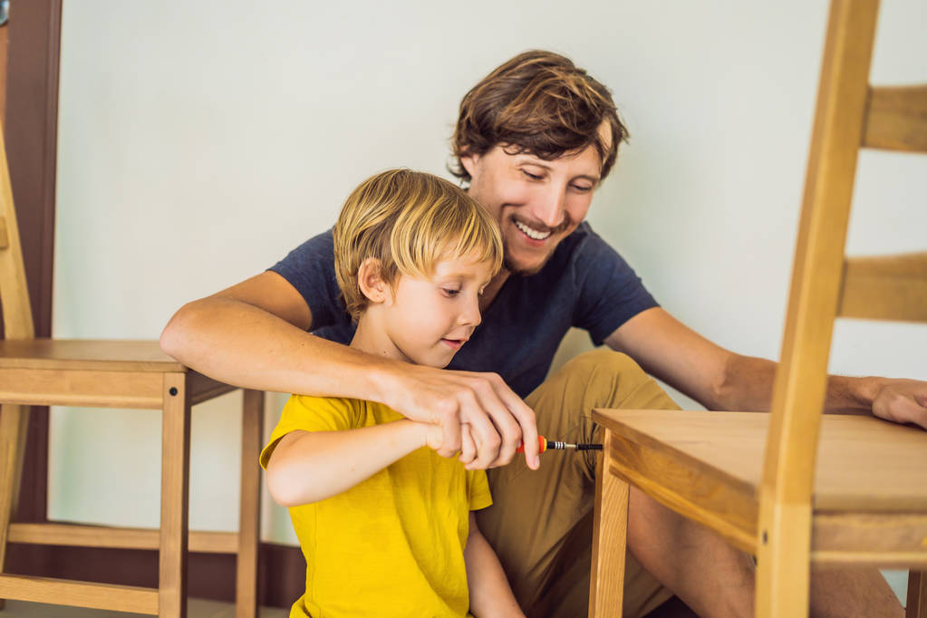 Vader en zoon monteren meubels. Een jongen die zijn vader thuis helpt. Happy Family concept - Foto, afbeelding