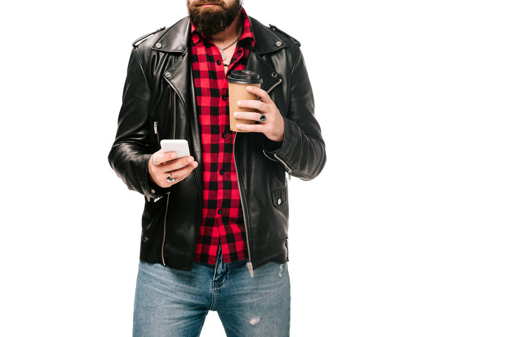 obcięty widok człowieka w czarną skórzaną kurtkę, trzymając kawa na wynos i za pomocą smartfona, na białym tle - Zdjęcie, obraz