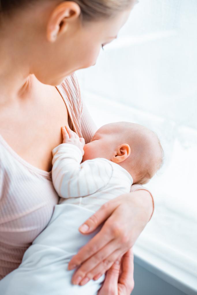 bijgesneden schot van jonge moeder borstvoeding schattig baby thuis - Foto, afbeelding