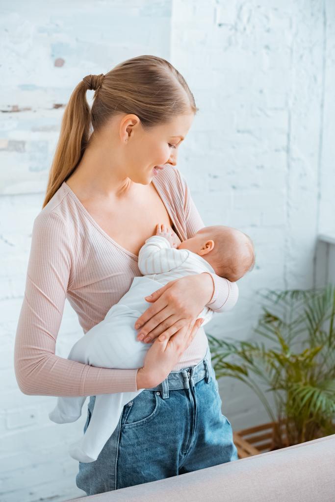 szép mosolygó fiatal anya szoptatás babának otthon   - Fotó, kép