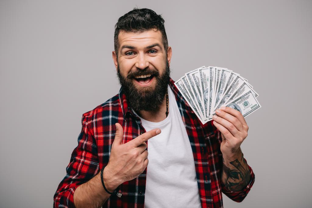 excited bearded man pointing at dollar banknotes isolated on grey - Photo, Image