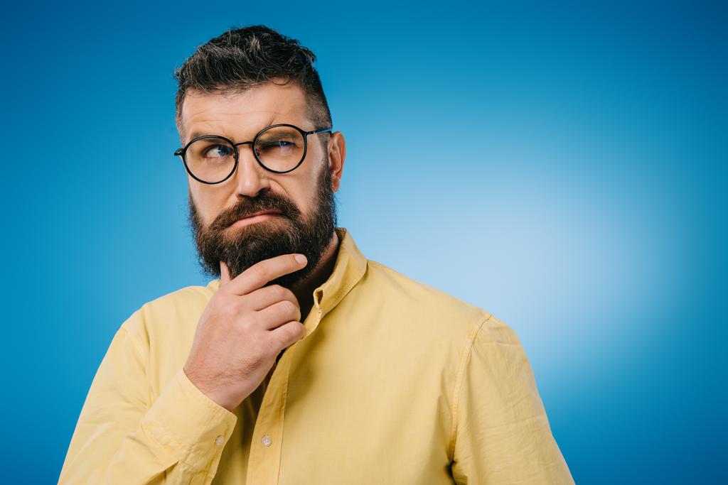 suspicious bearded man in eyeglasses isolated on blue - Photo, Image