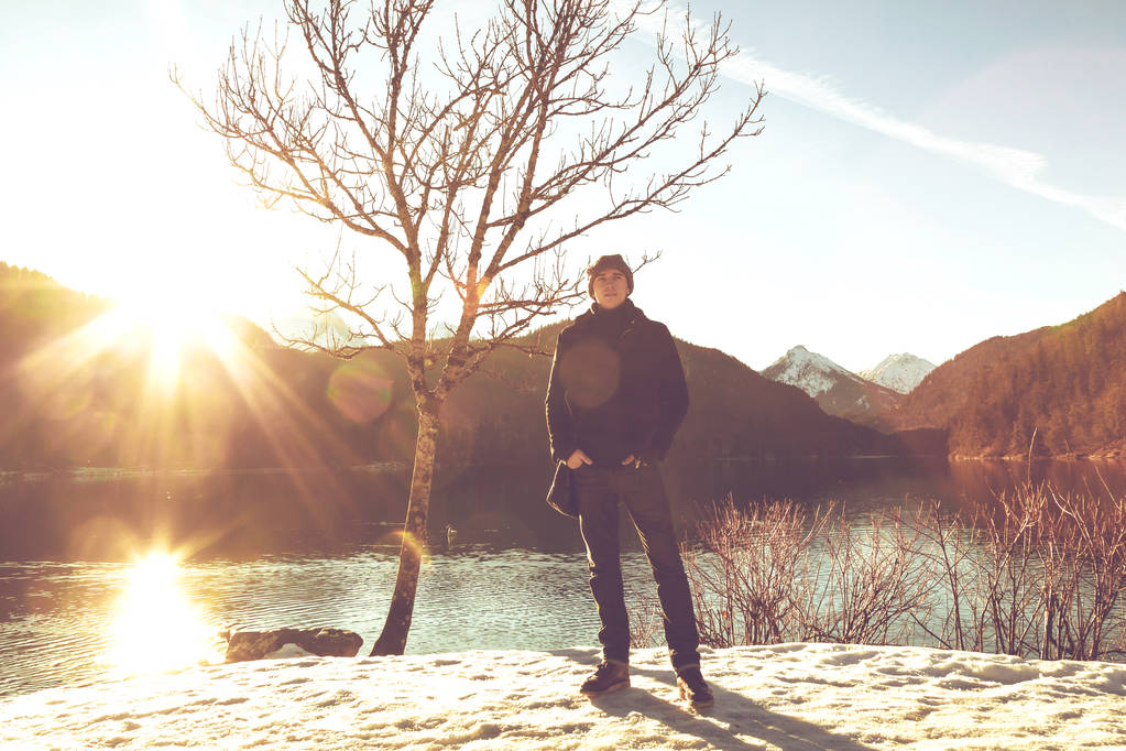 pohledný mladý muž stojící v blízkosti jezera v zimních horách - Fotografie, Obrázek