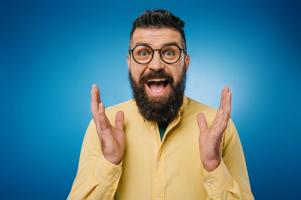 nadšený vousatý muž v brýlích ukázal izolované na modré - Fotografie, Obrázek