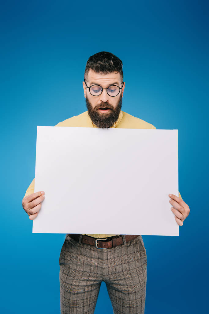 surprised man holding empty board isolated on blue - Photo, Image
