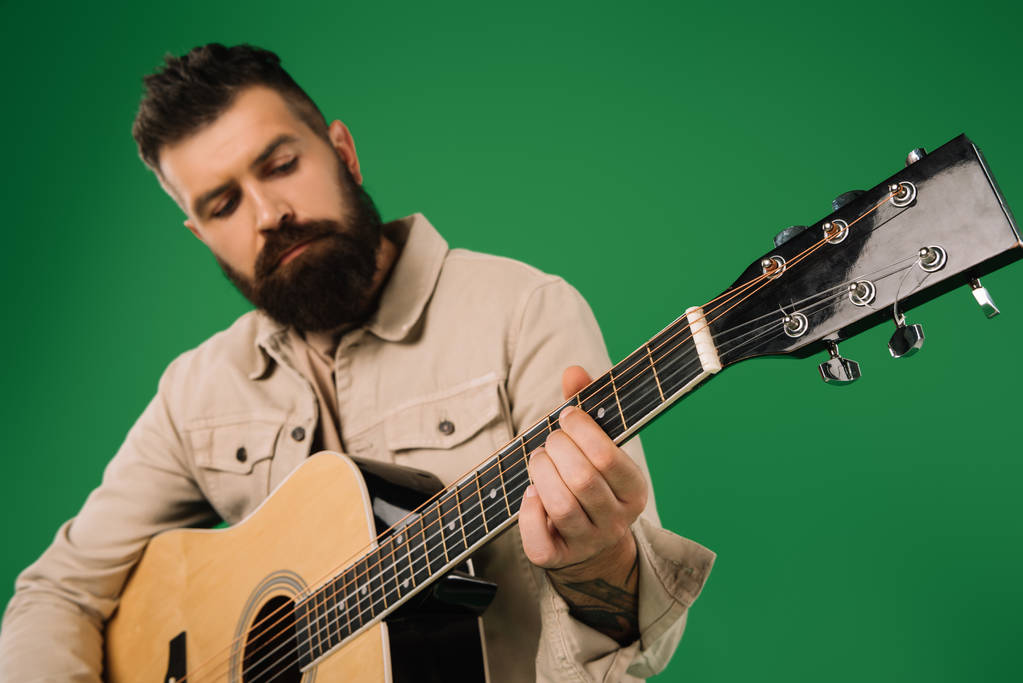 pohledný muž hraje na akustickou kytaru, izolované na zelené - Fotografie, Obrázek