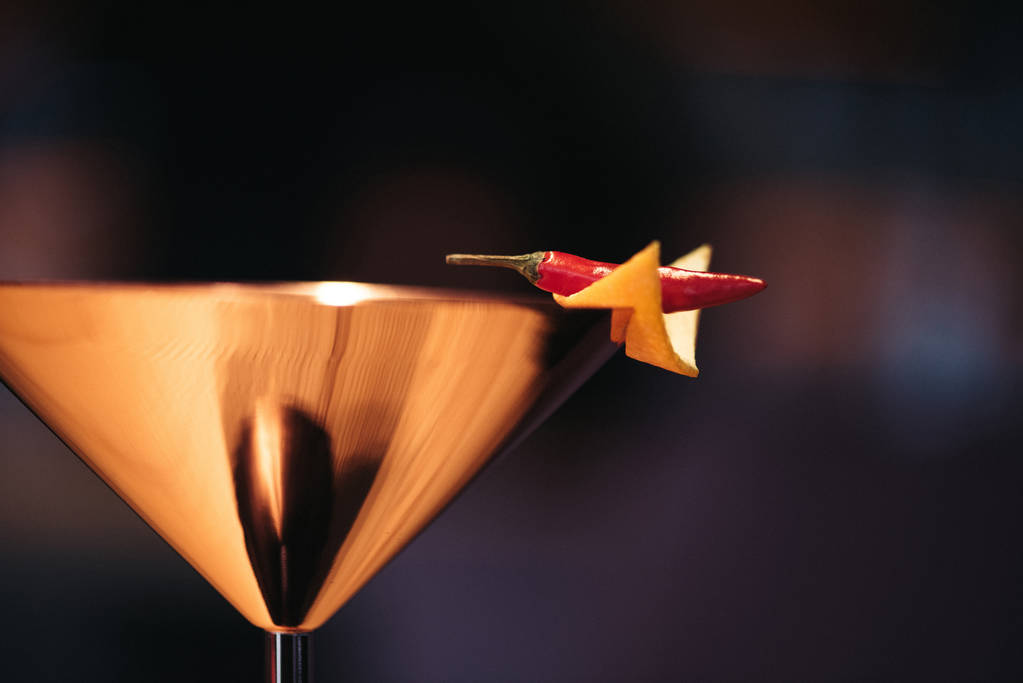Nahaufnahme eines alkoholischen Cocktails in Metallglas mit Chilischote und Nacho-Chip auf dunklem Hintergrund - Foto, Bild