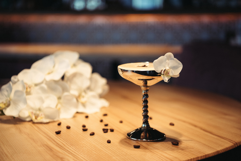 foco seletivo de coquetel alcoólico em vidro de metal decorado com flor de orquídea e grãos de café em fundo escuro
 - Foto, Imagem