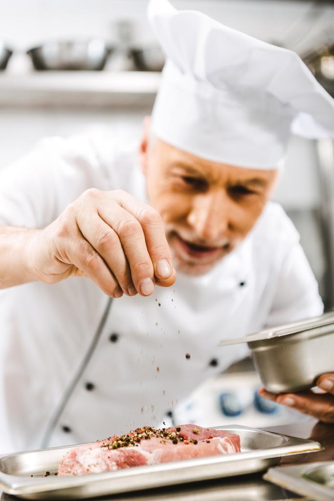 miespuolinen kokki yhtenäinen mausteita lihaa ravintolassa keittiö
 - Valokuva, kuva