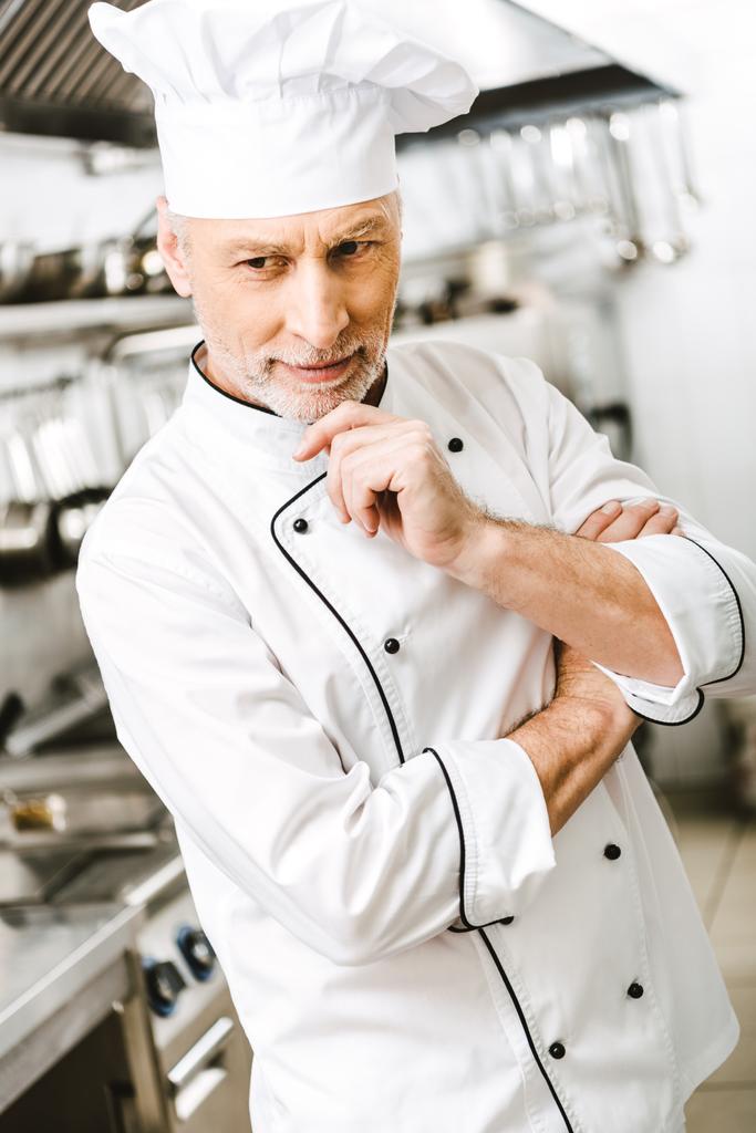 foco seletivo de bonito Chef masculino pensativo apoiando queixo com a mão na cozinha do restaurante
 - Foto, Imagem