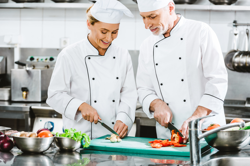 чоловічі і жіночі шеф-кухаря в двобортний куртки, приготування їжі в кухні ресторану - Фото, зображення