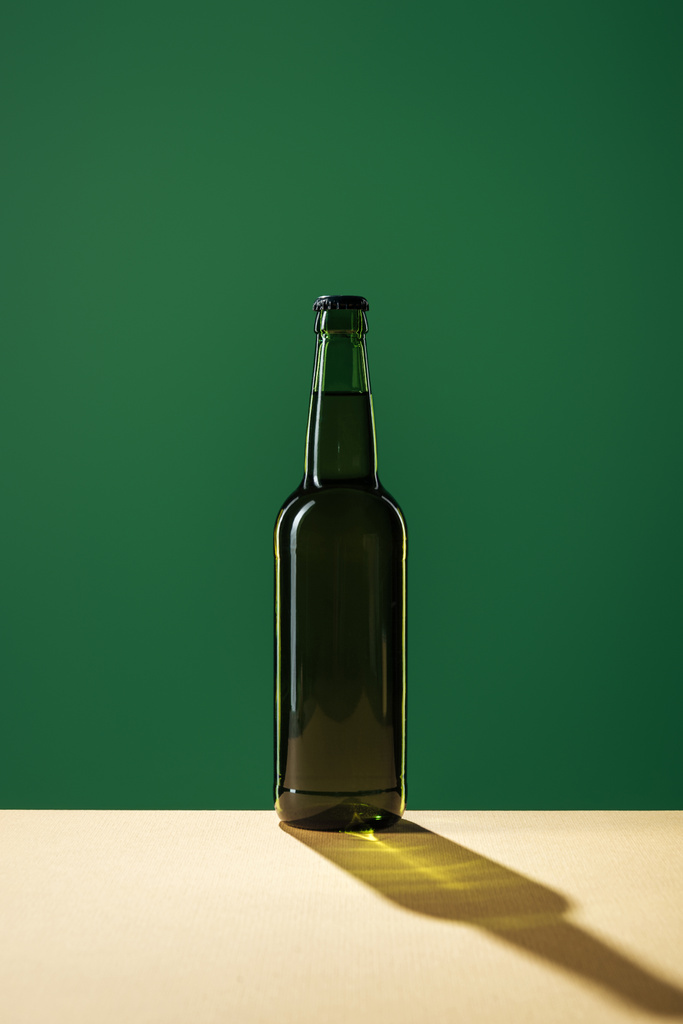 pivní láhev se stínem izolovaných na zelené, st patrick day koncept - Fotografie, Obrázek