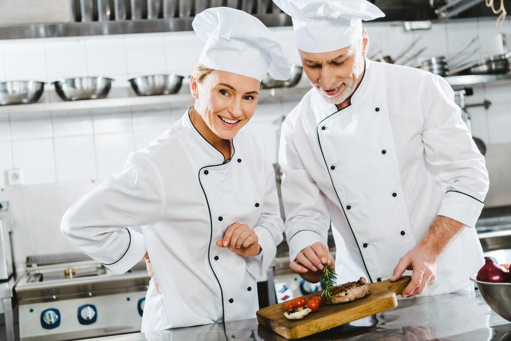 肉ステーキ レストランのキッチンで木の板に制服を着た女性と男性のシェフ - 写真・画像