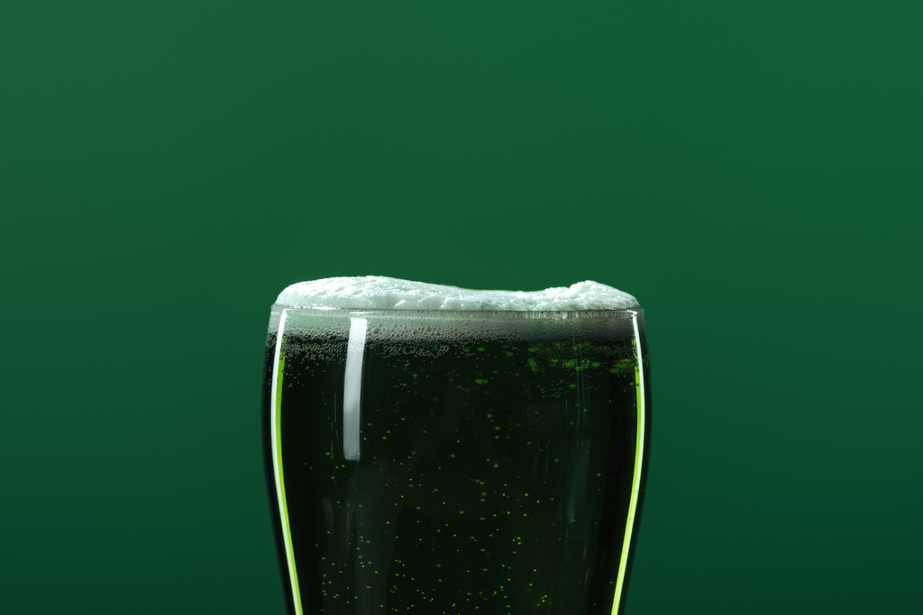 стакан пива с пеной, изолированной на зеленом с копировальным пространством, концепция дня Святого Патрика
 - Фото, изображение