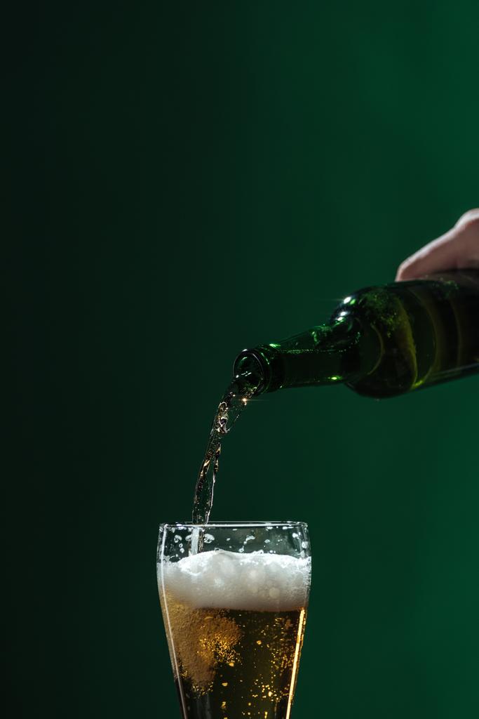 наливая пиво в стакан с пеной, изолированной на зеленой концепции дня Святого Патрика
 - Фото, изображение